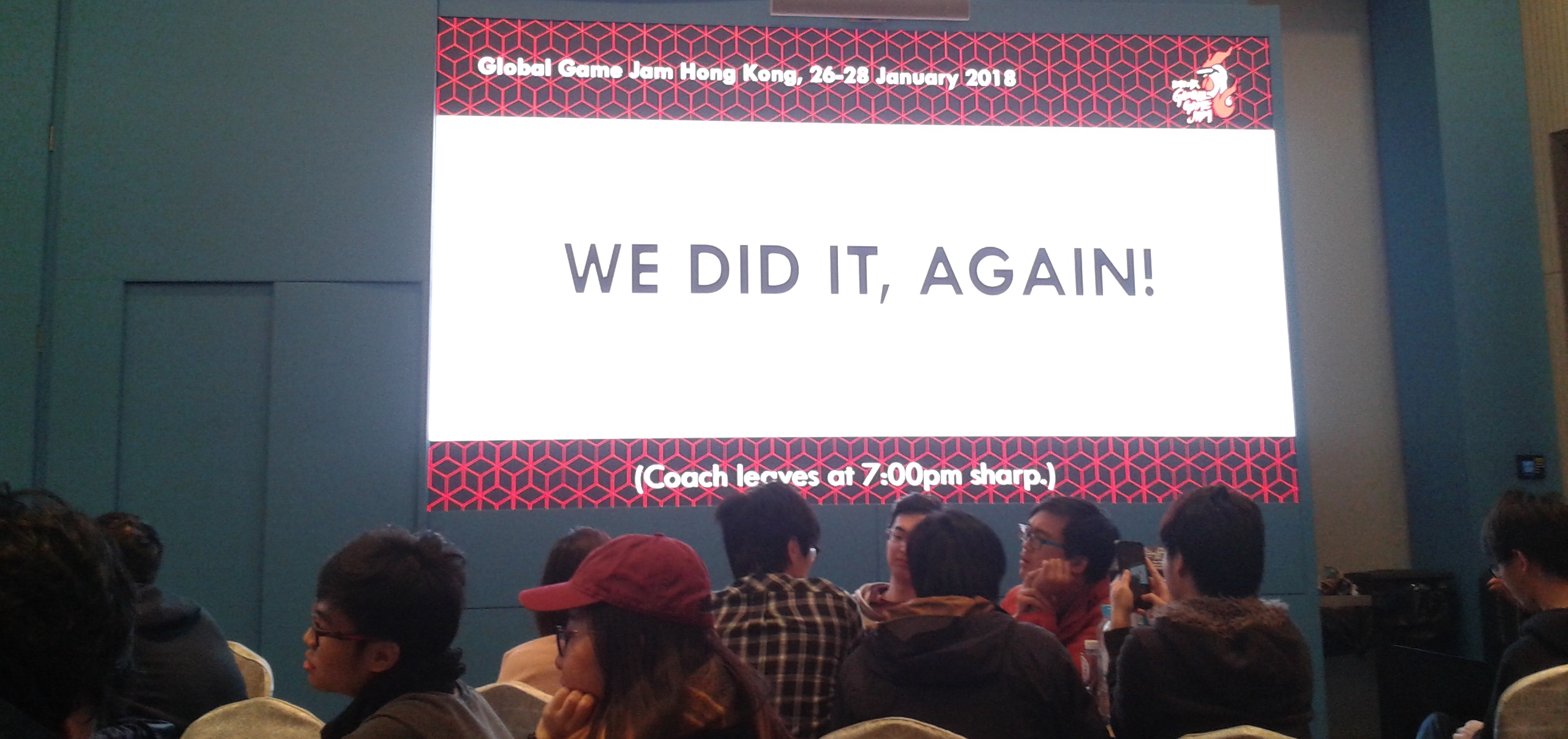 GGJ Venue with a big screen showing a Powerpoint slide with the words "WE DID IT, AGAIN!"