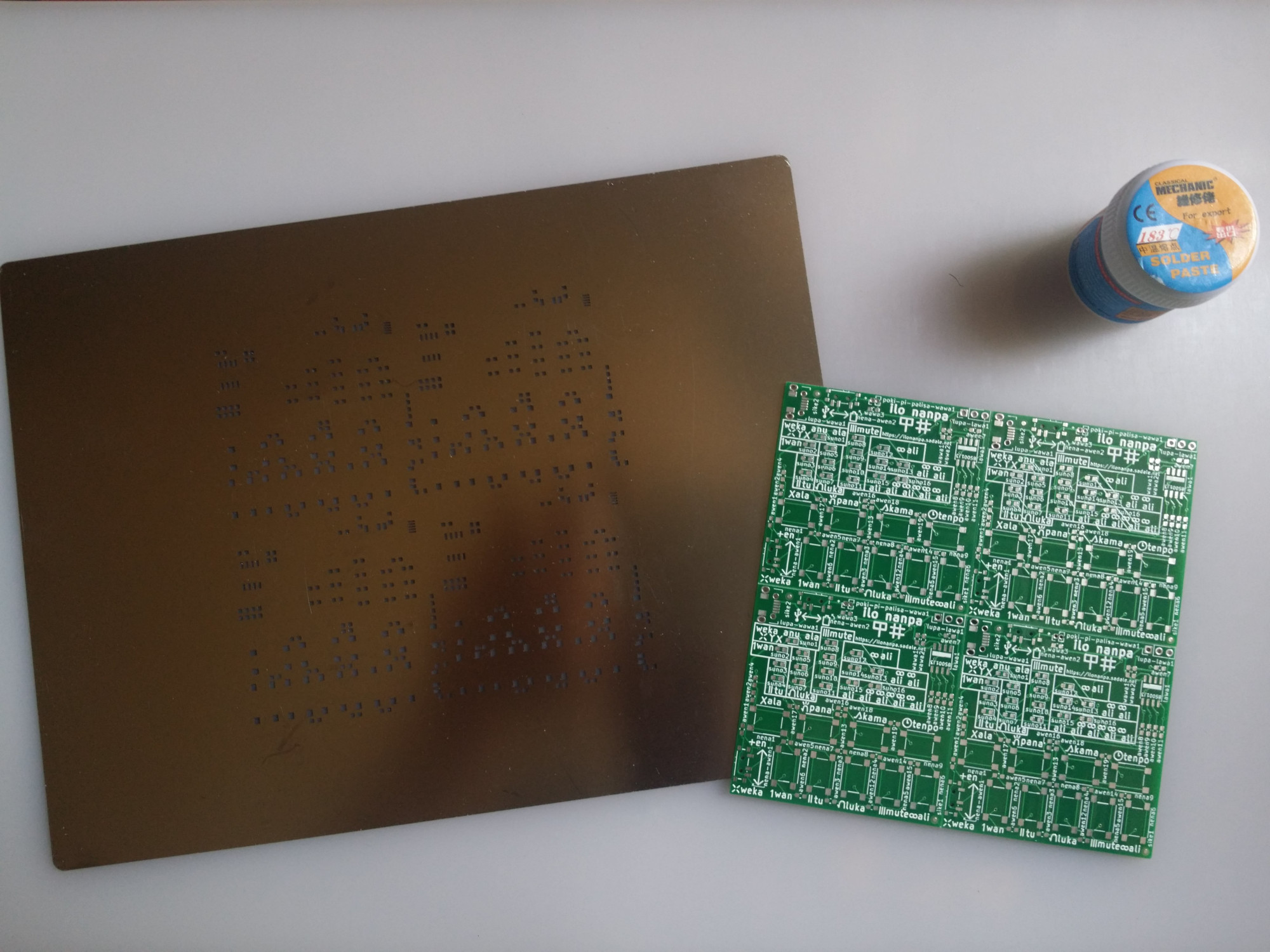 a jar of solder paste, panelized PCB and a stencil on a heat-resistant mat